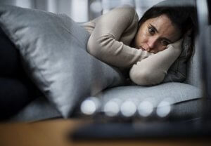 A woman lies on her side as she experiences detox withdrawal symptoms